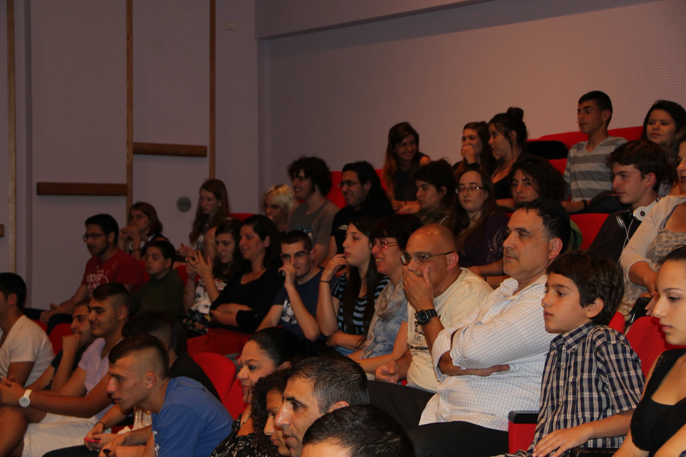 a crowd of people sitting in an auditorium looking at soing