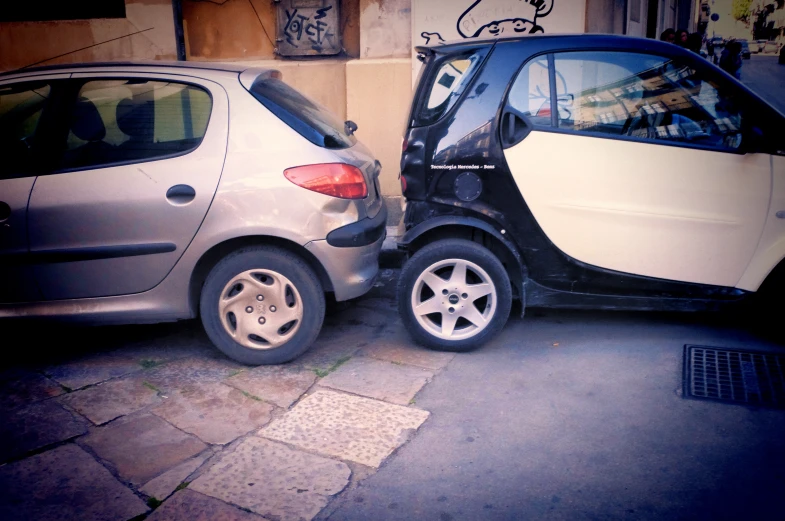 a smart car has its wheel still down while another vehicle is parked near it