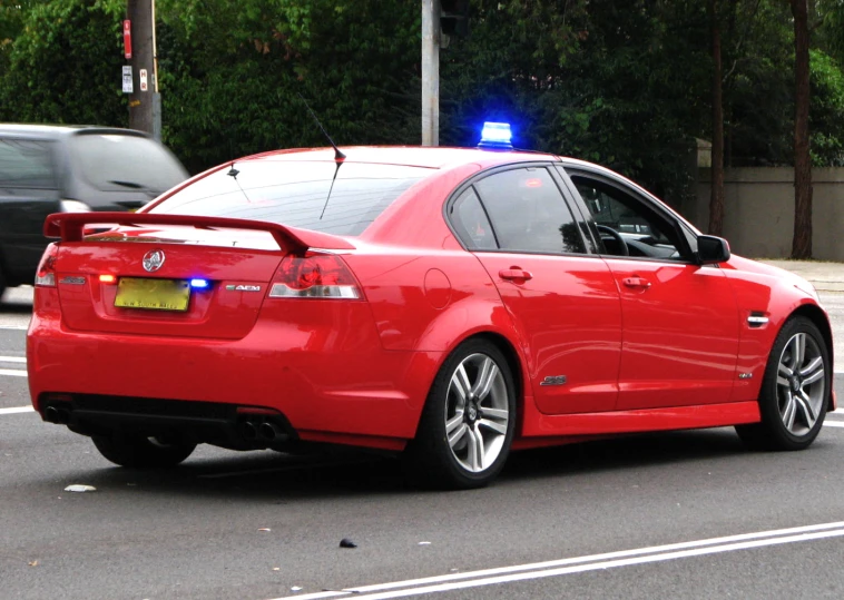 a red sedan is stopped at an intersection
