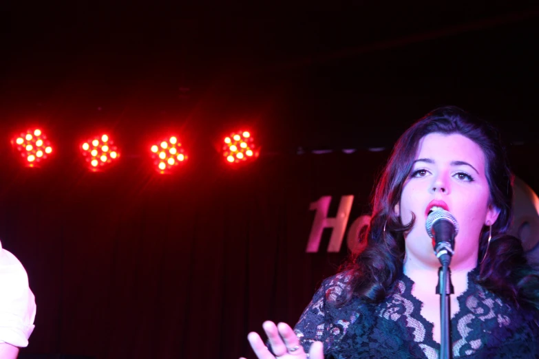 woman standing up at a microphone on stage while someone is on the mic