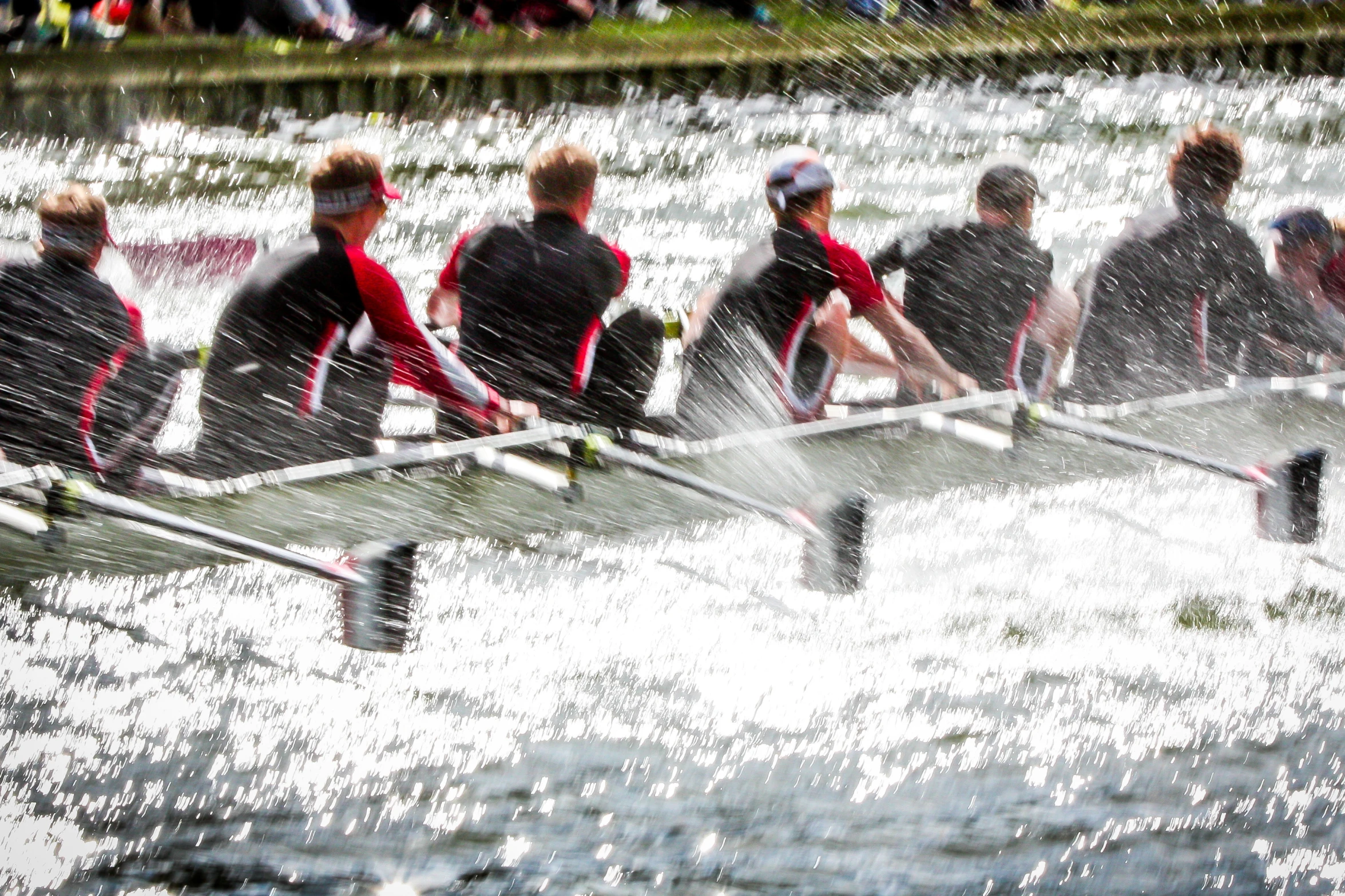 several rowers rowing on water near a crowd