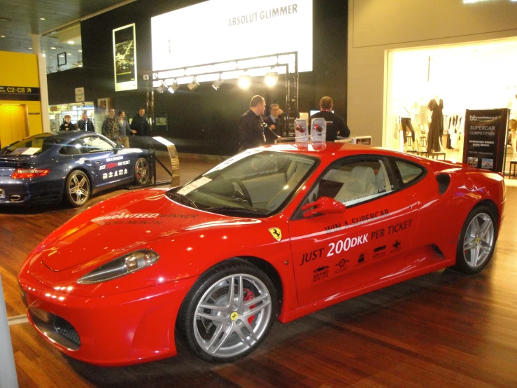 people looking at a very fancy car in a showroom