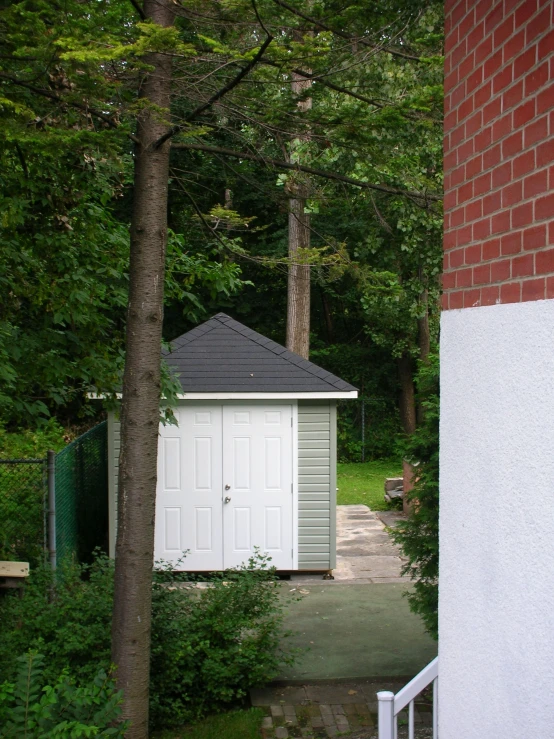 the house is located in front of a fence and trees