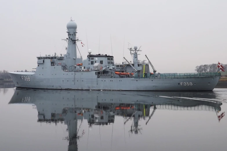 a big gray ship in the water with some clouds