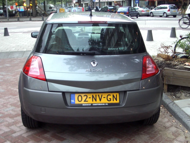 the back view of a small car parked on a cobblestone road