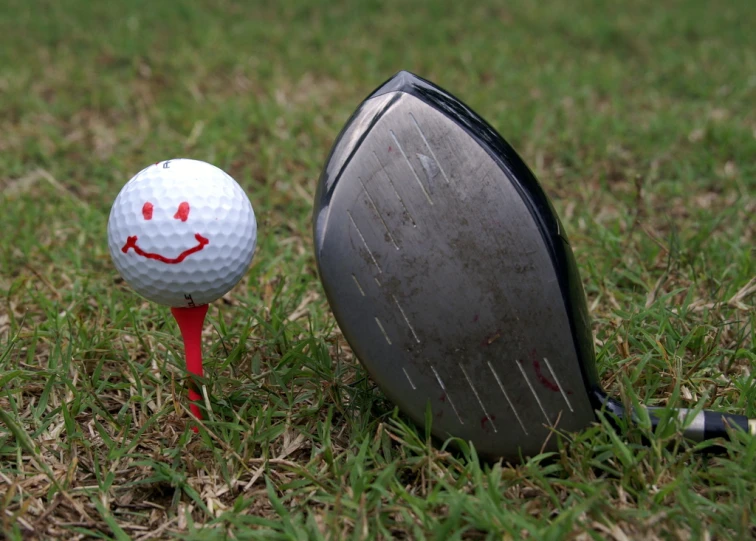 an open golf ball sitting in the grass next to a golf club