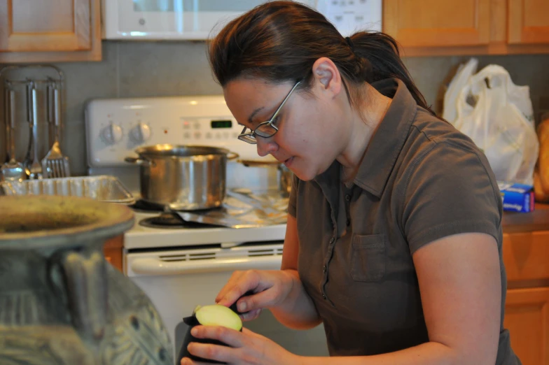 a woman standing in a kitchen using a grinder