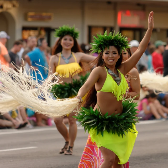 woman in a yellow and green bikini and grass skirt, dancing while others watch