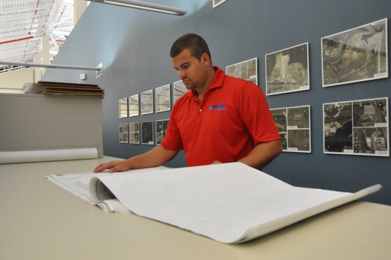 man wearing red shirt and glasses writing on large sheet of paper