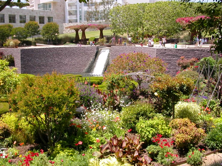 the waterfall in the middle of the park is surrounded by various flowers
