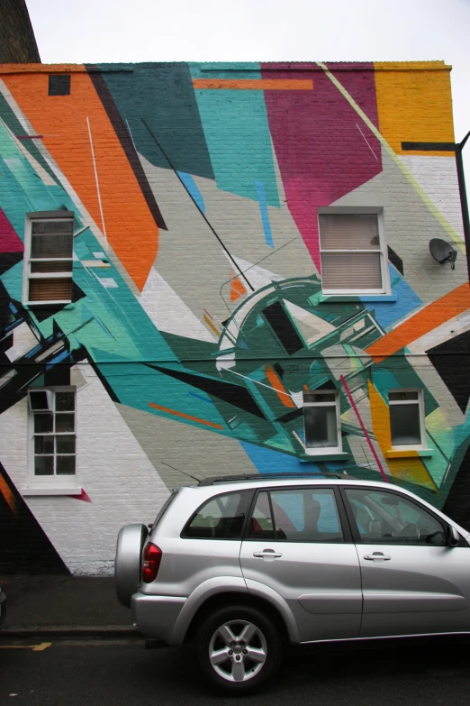 a car parked in front of a mural on a building
