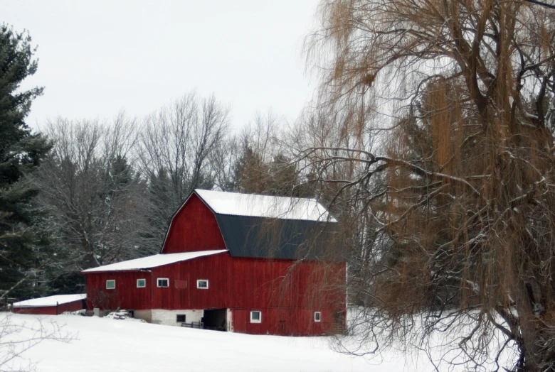 a red barn is next to some bare trees