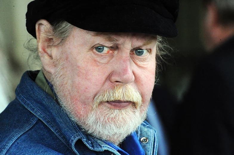 an old man wearing a black beret and blue jacket