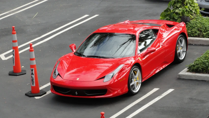 a red sports car driving by two traffic cones