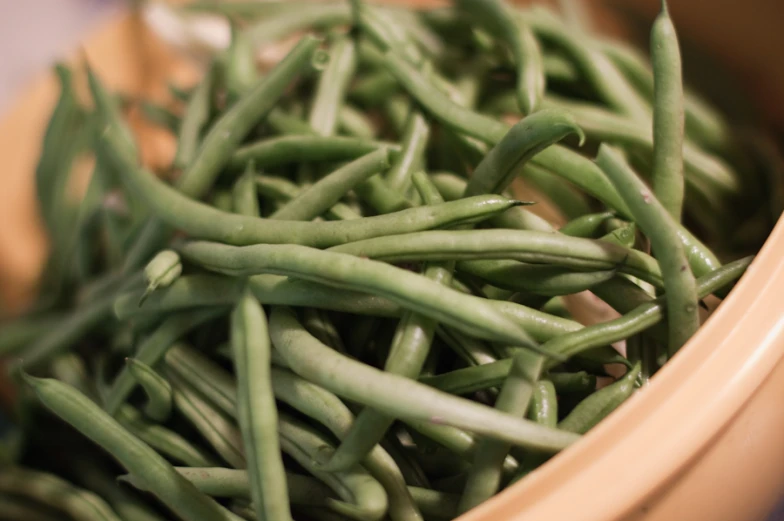 a bowl filled with green beans sitting on top of a table