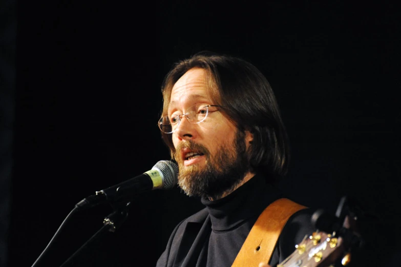 a man playing guitar in front of a microphone