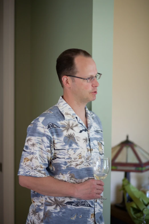 a man wearing glasses and a shirt holding a wine glass