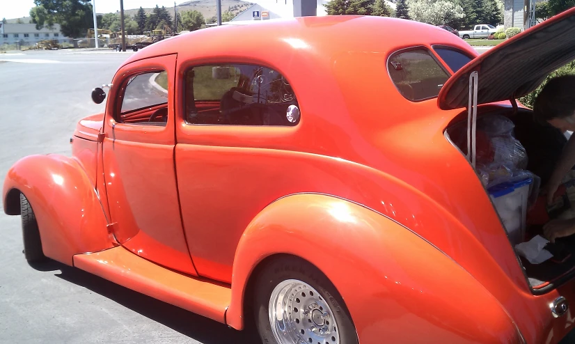 an old fashioned orange car with people in the back