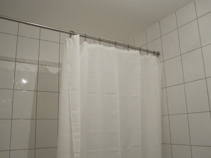 a shower with white tiled walls and curtains