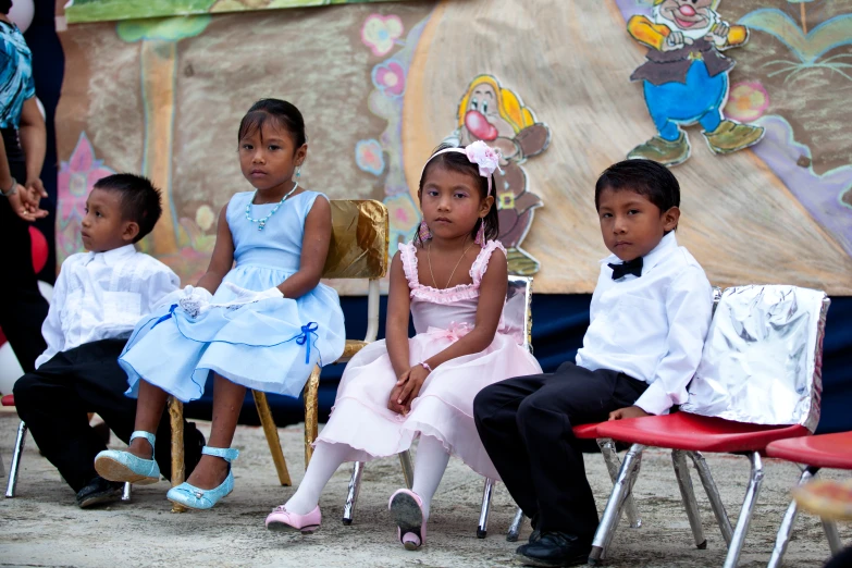 five children dressed in traditional clothing sit together