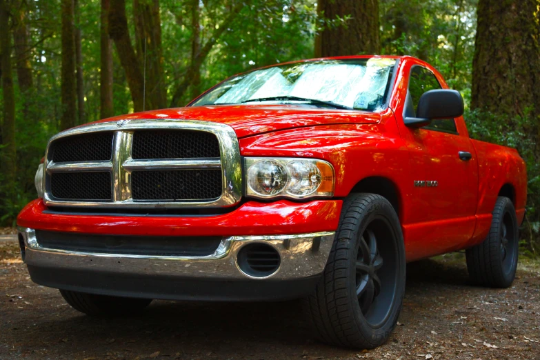 a bright red pick up truck parked in the woods