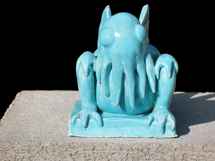 a blue plastic elephant statue sitting in the sand