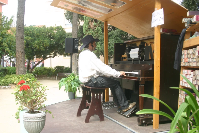 a man in hat and sunglasses playing piano outside