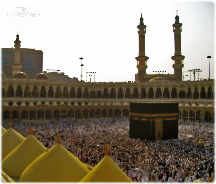 people stand around a mosque during the day