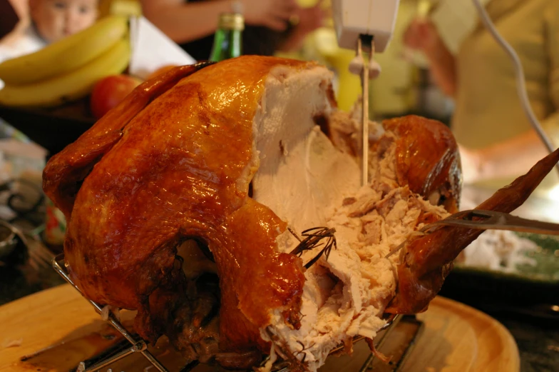 a large roasted chicken being cut up with a fork