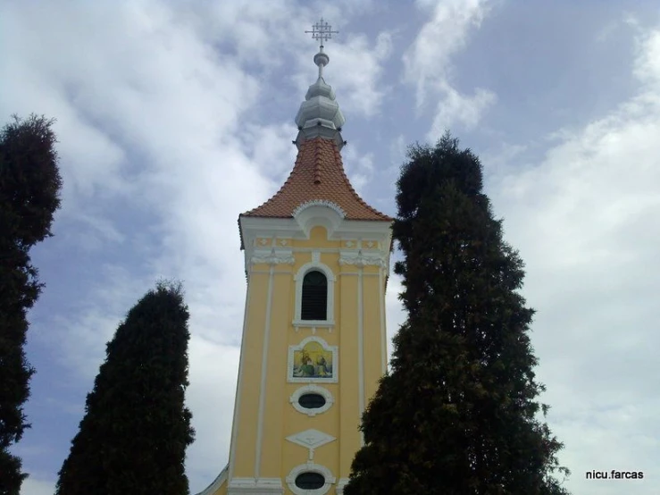 a tower in front of several trees and cloudy sky