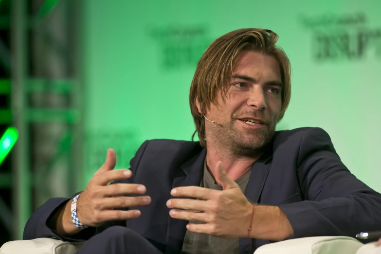 a man is talking into the camera while sitting in a chair