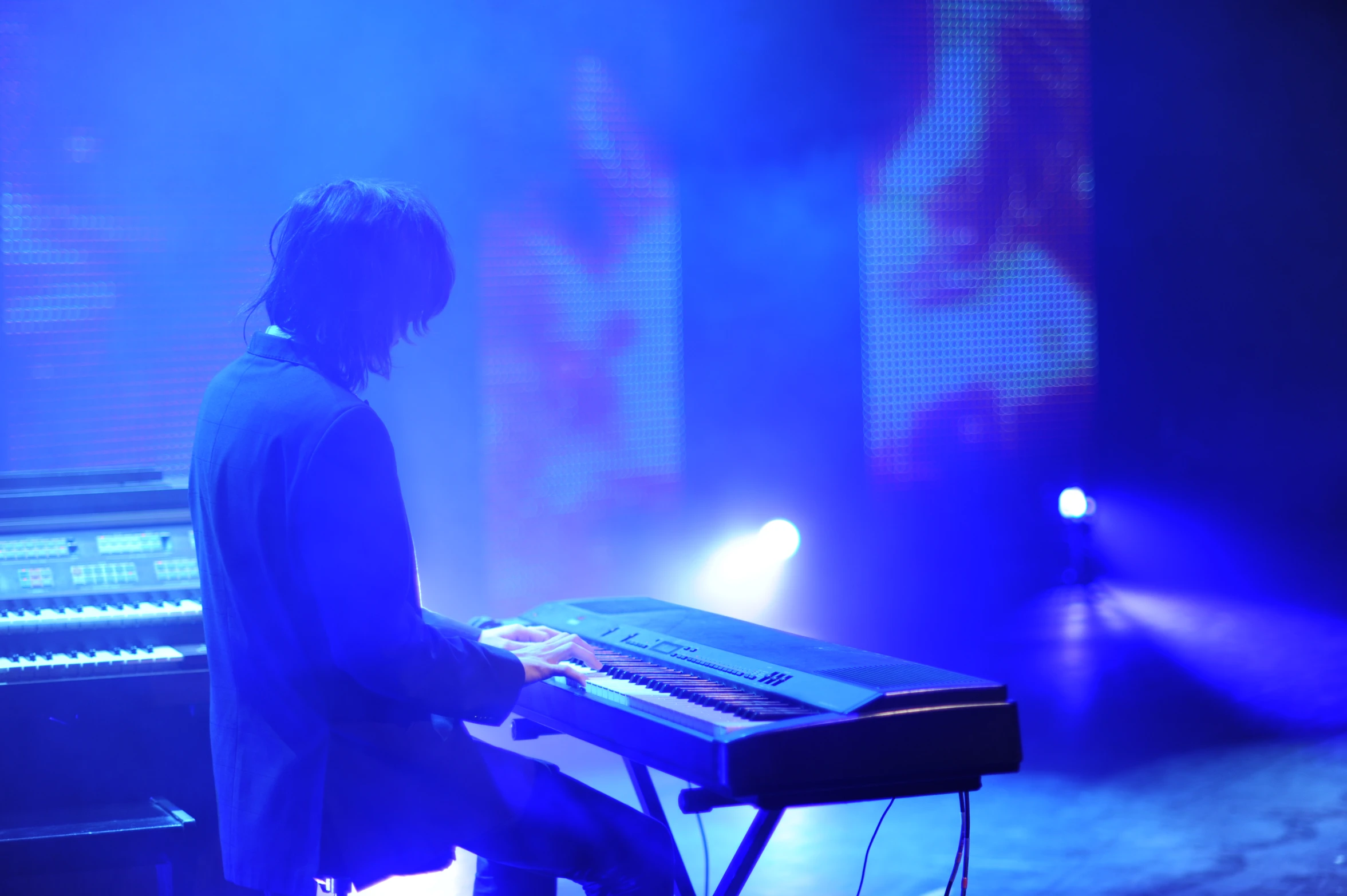 a male in a black jacket is playing a keyboard