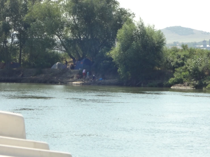 campers sitting next to a river and camping site