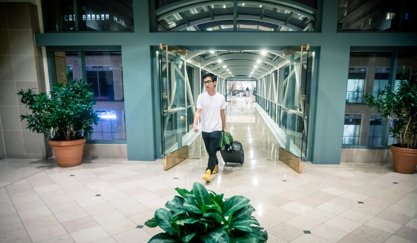 man walking in front of a building holding luggage