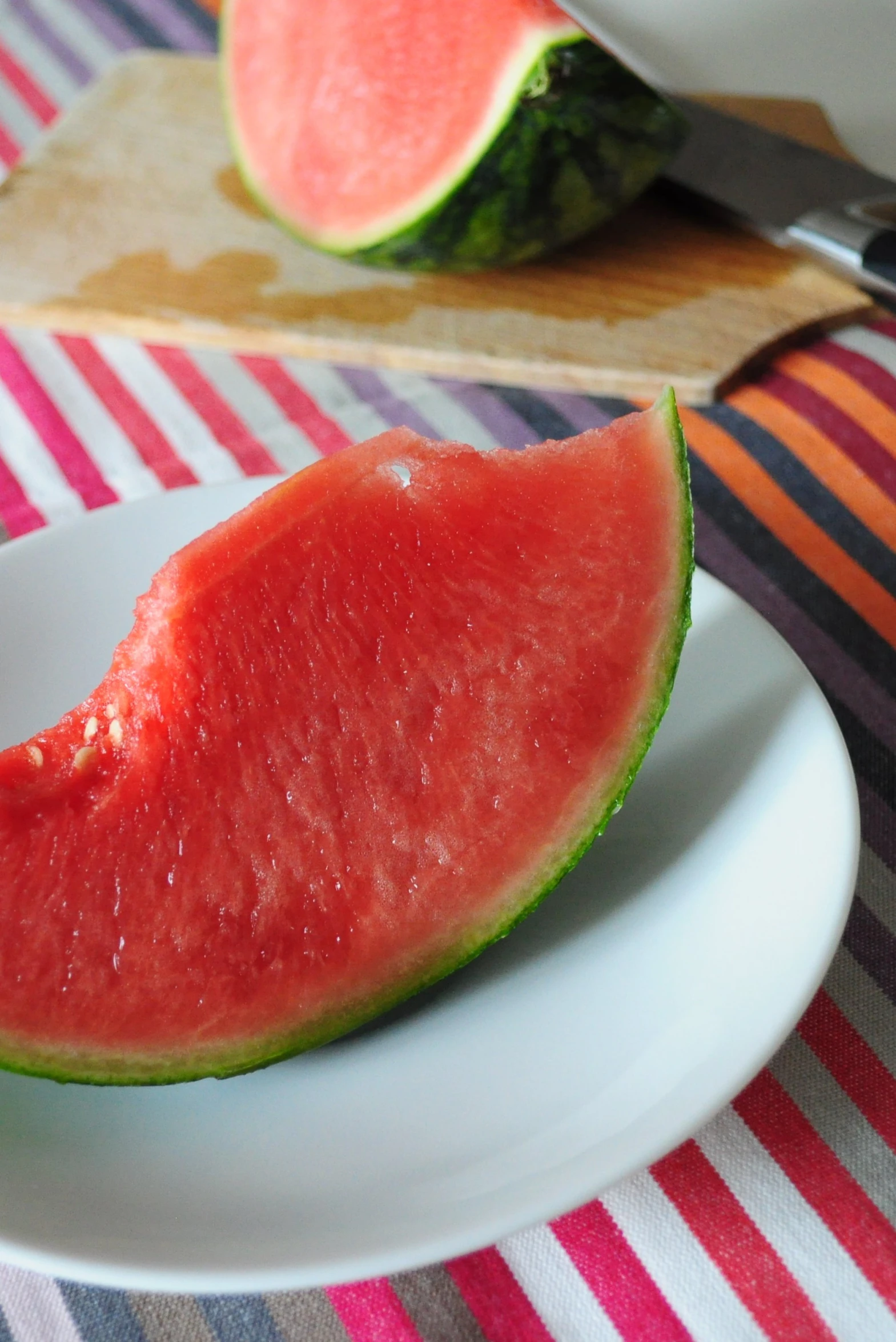 a slice of watermelon being cut in half on a white plate