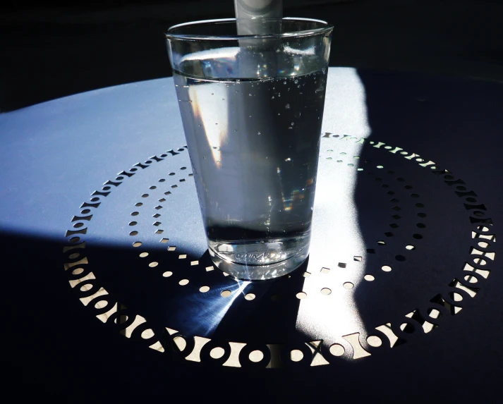 a glass with a silver spoon and some water on a table
