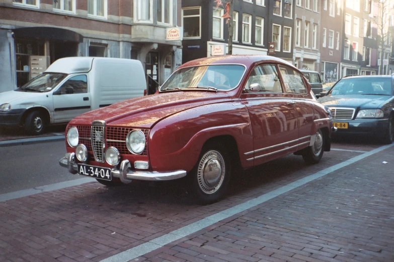 a red car driving down a street next to tall buildings