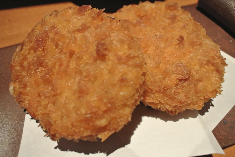 two fried donuts that are sitting on a piece of paper