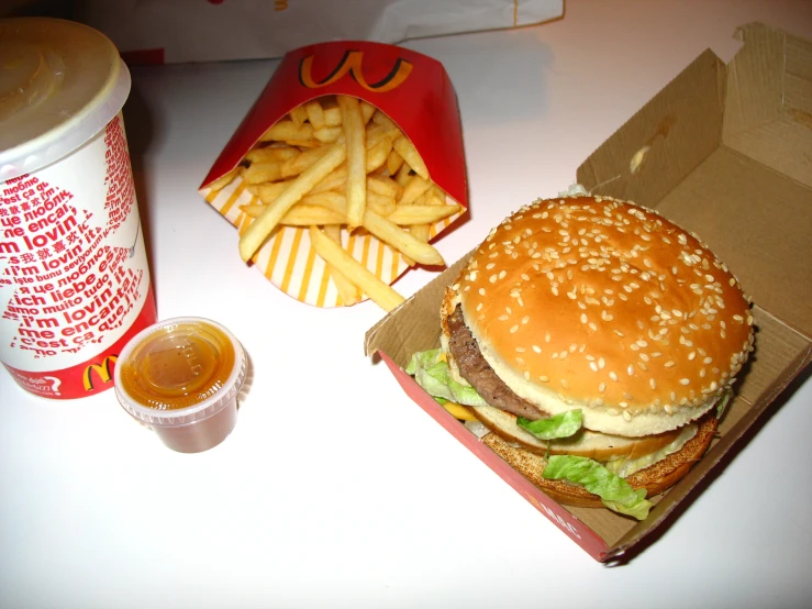 a hamburger sitting on top of a table next to french fries and soda