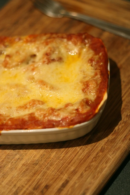 a close up view of a baked cheese dish on a  board