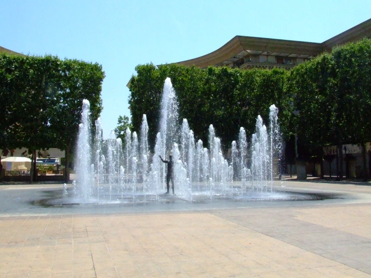 a fountain is in the center of a street surrounded by trees