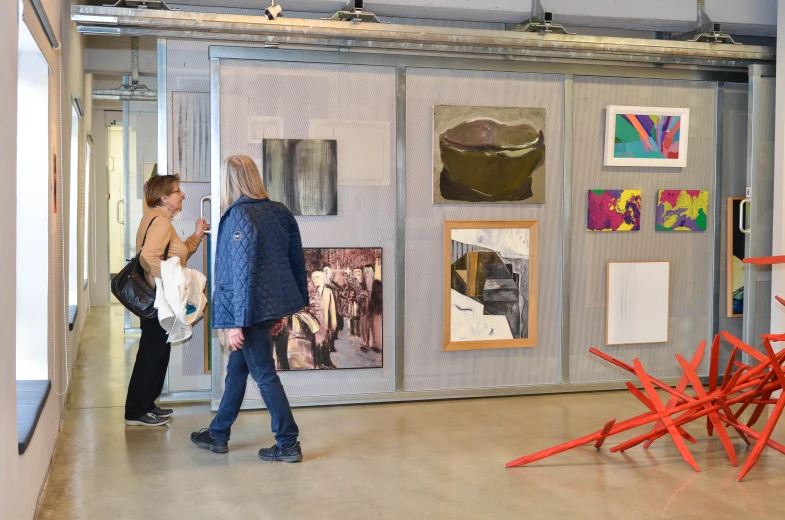 two people in a room with some paintings