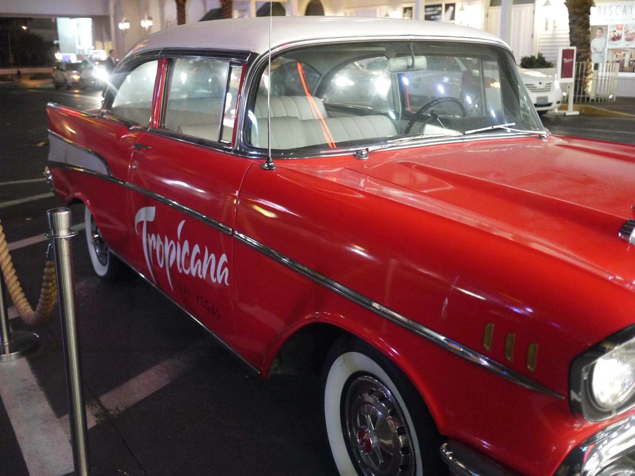 a red and white classic car is parked on the street