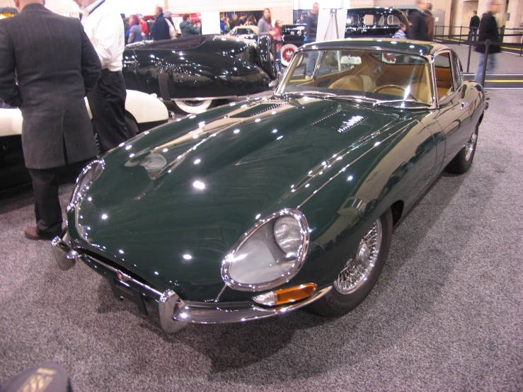 an antique green sports car on display at a show