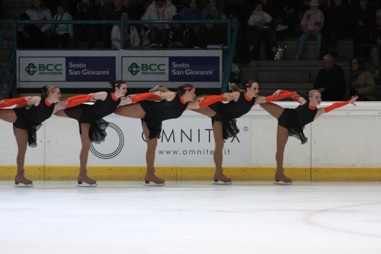 four women in black and orange outfits performing a routine