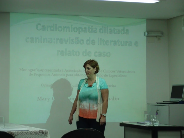 a woman in a blue shirt standing in front of a projector screen