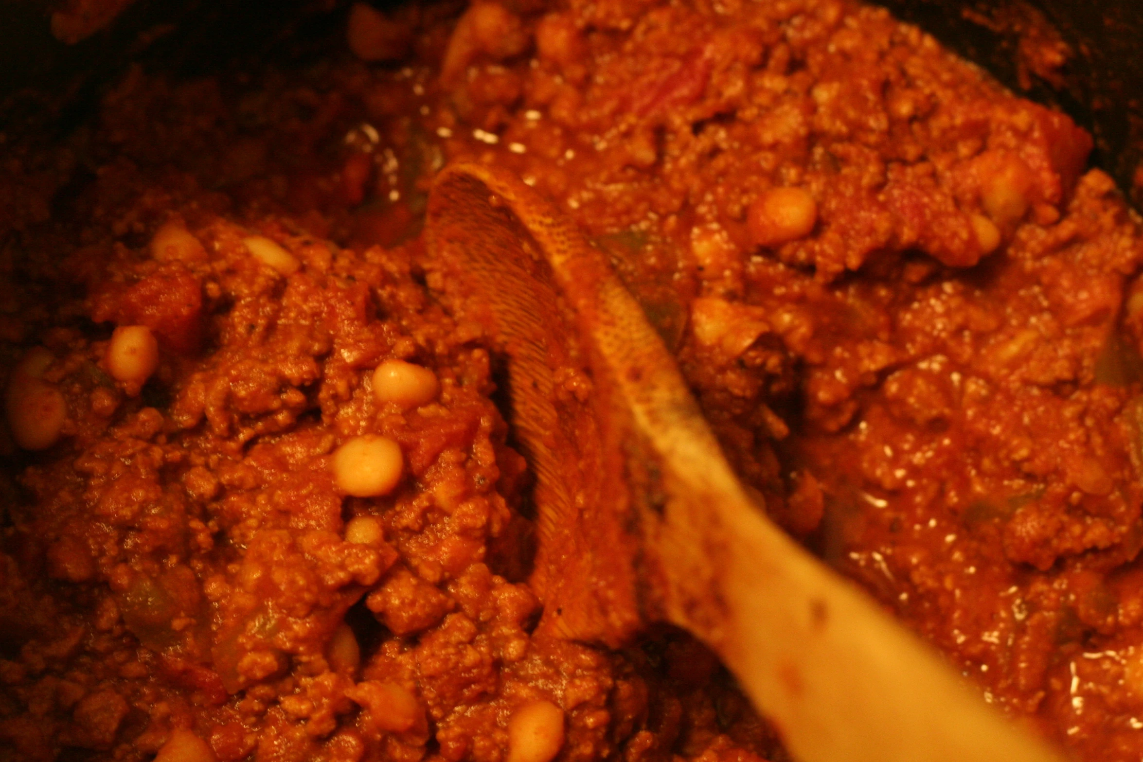 a wooden spoon stirring meat in chili