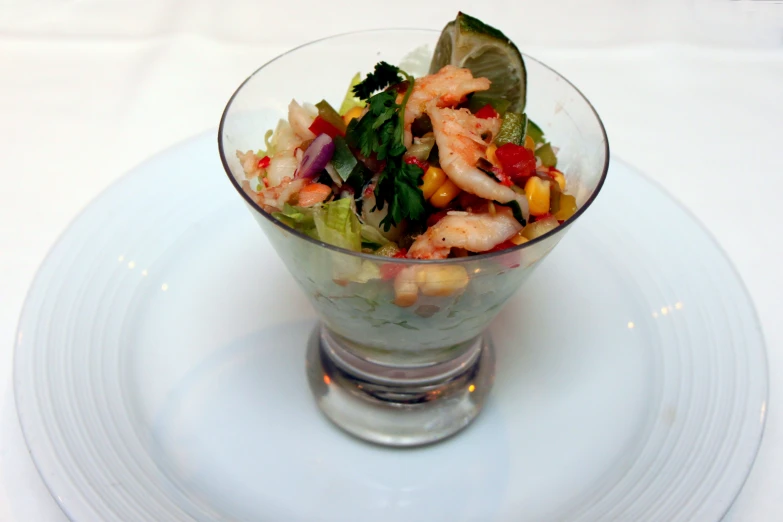 a dish of shrimp, lettuce, tomato and garnish with lemon wedges