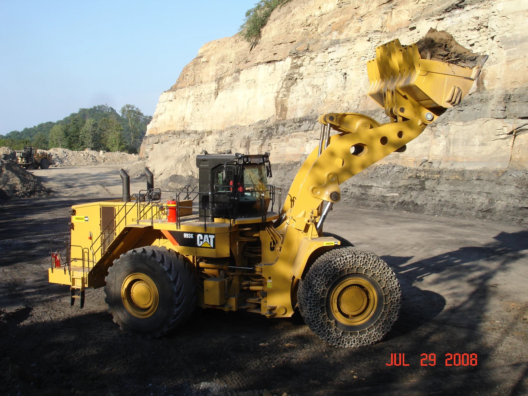 a tractor is parked in the shade near a hill