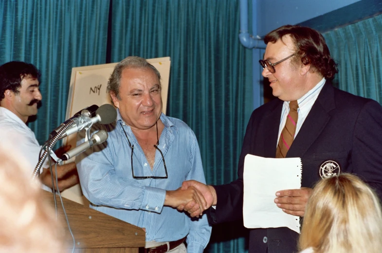 a man standing next to another man with a microphone